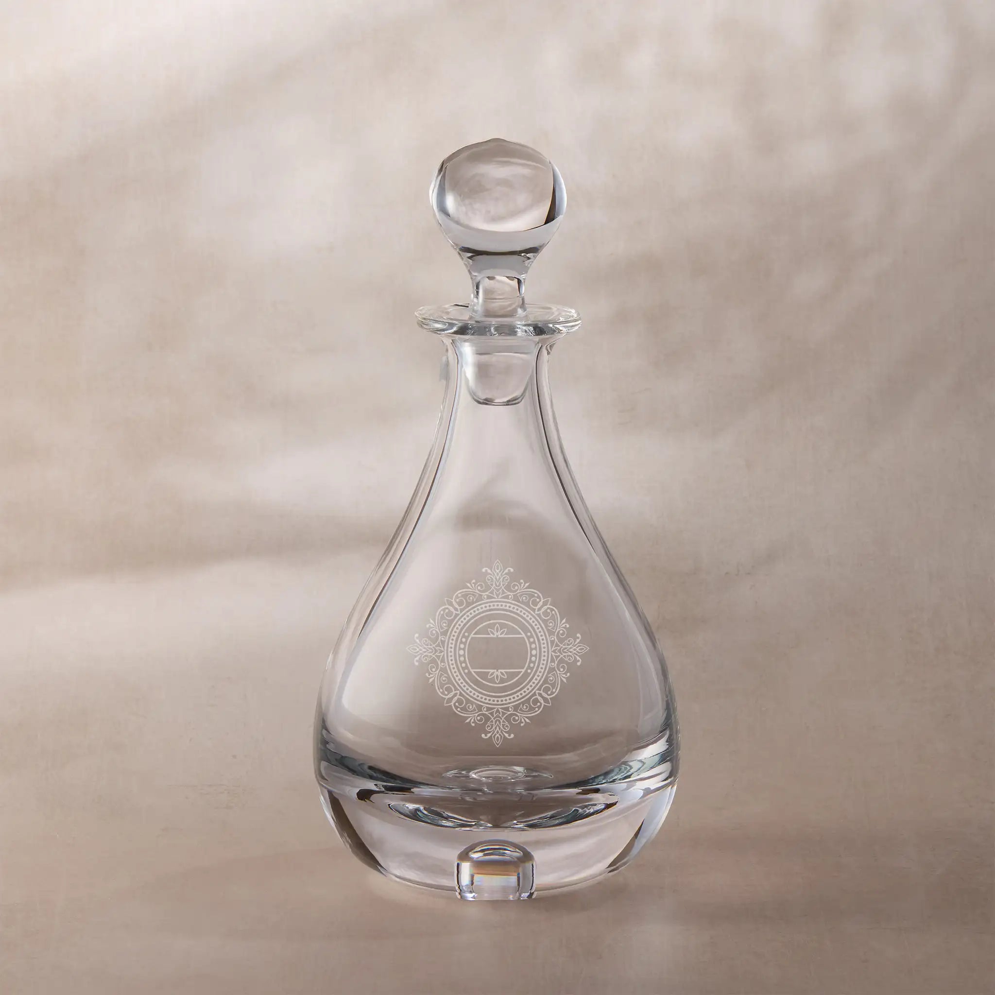 Clear glass decanter with decorative chantilly lace design on a beige background
