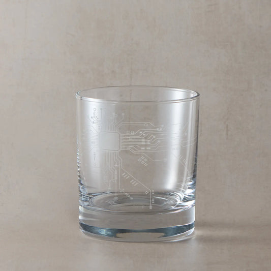 Whisky glass engraved with a circuit board, photographed on a light background