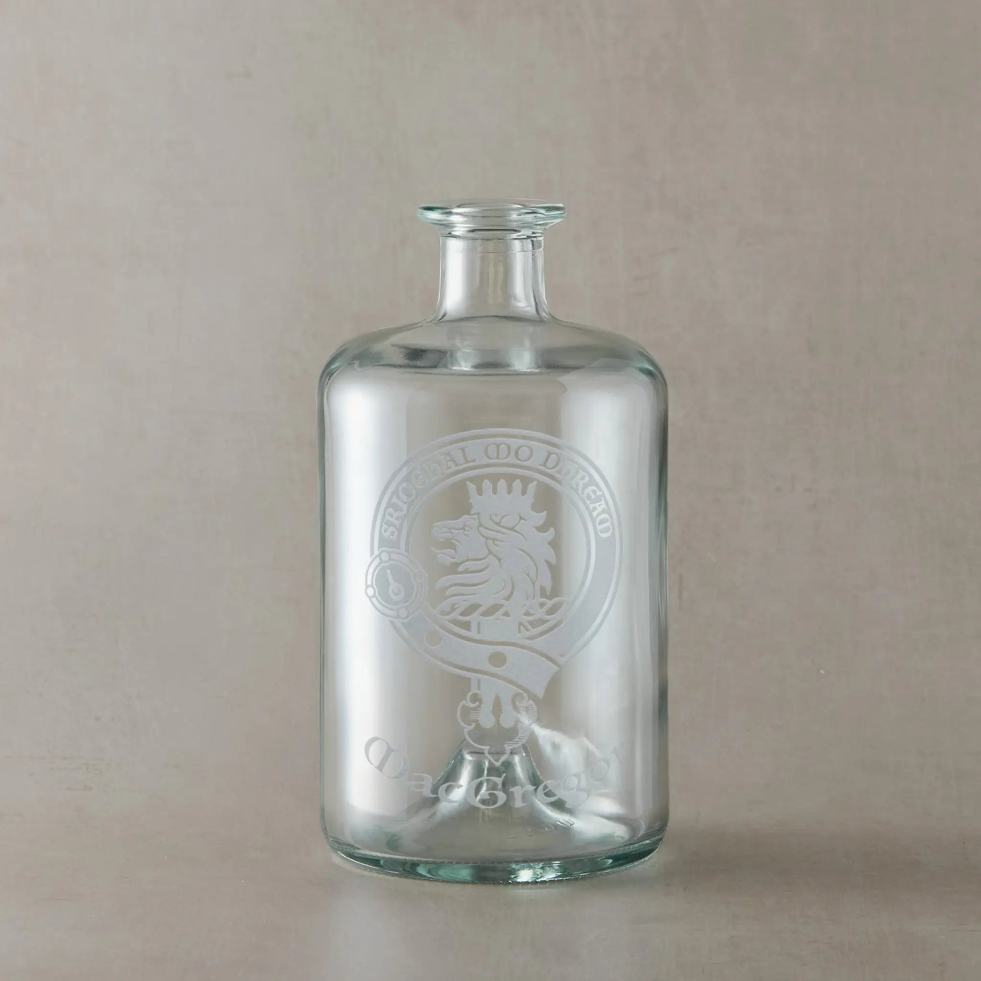 Glass apothecary decanter bottle engraved with Scottish clan crestm motto and surname design on a beige background