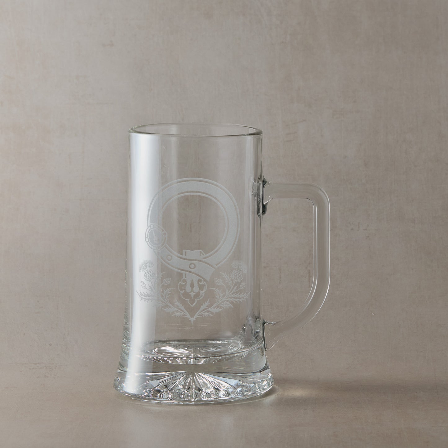 Clear glass tankard with engraved Scottish Clan Crest buckle and thistles with handle on the right