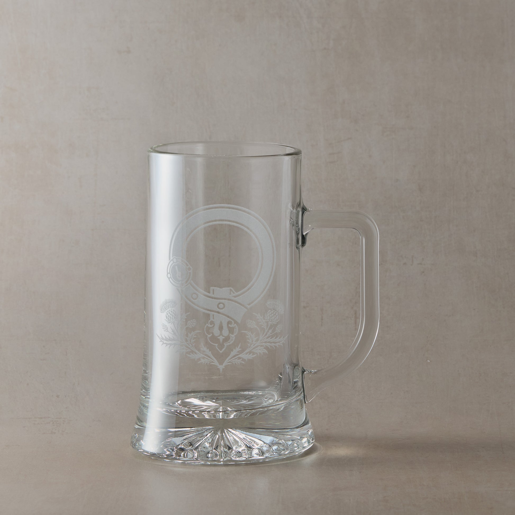 Clear glass tankard with engraved Scottish Clan Crest buckle and thistles with handle on the right