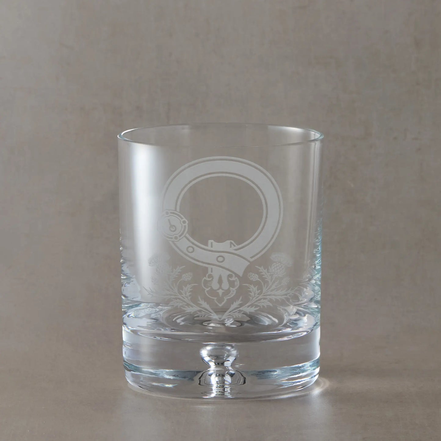 Whisky glass with intricate thistle and Scottish buckle design on a beige background