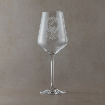 Engraved wine glass featuring a Scottish clan crest with belt and buckle motif, sandblasted on a clear Atelier wine glass against a neutral beige studio background