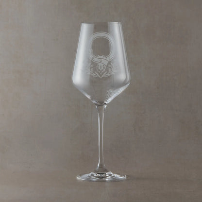 Wine glass with an engraved clan crest and thistle design on a grey background