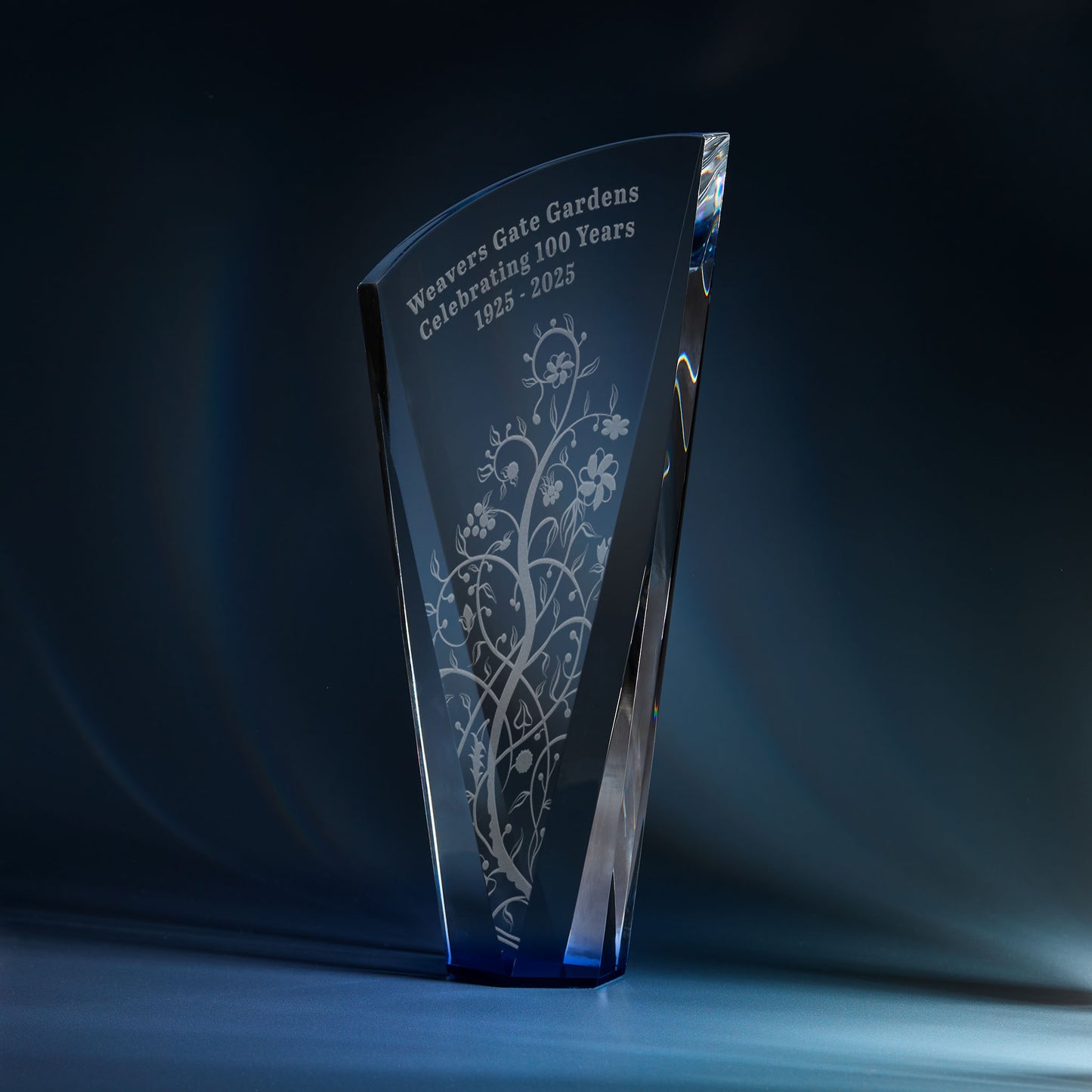 Engraved optical crystal shard award with sapphire blue base and corporate logo