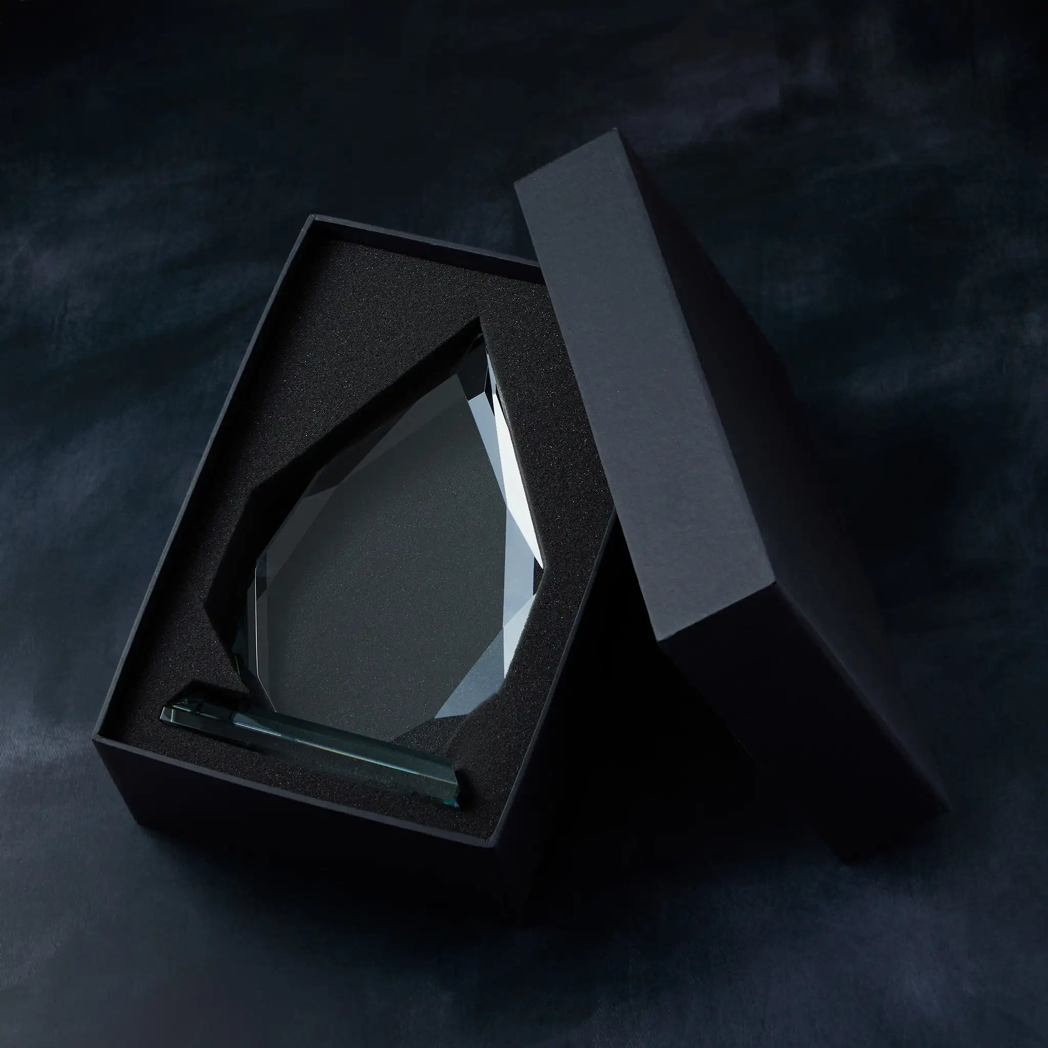 Crystal award displayed in a black presentation box ion a dark background