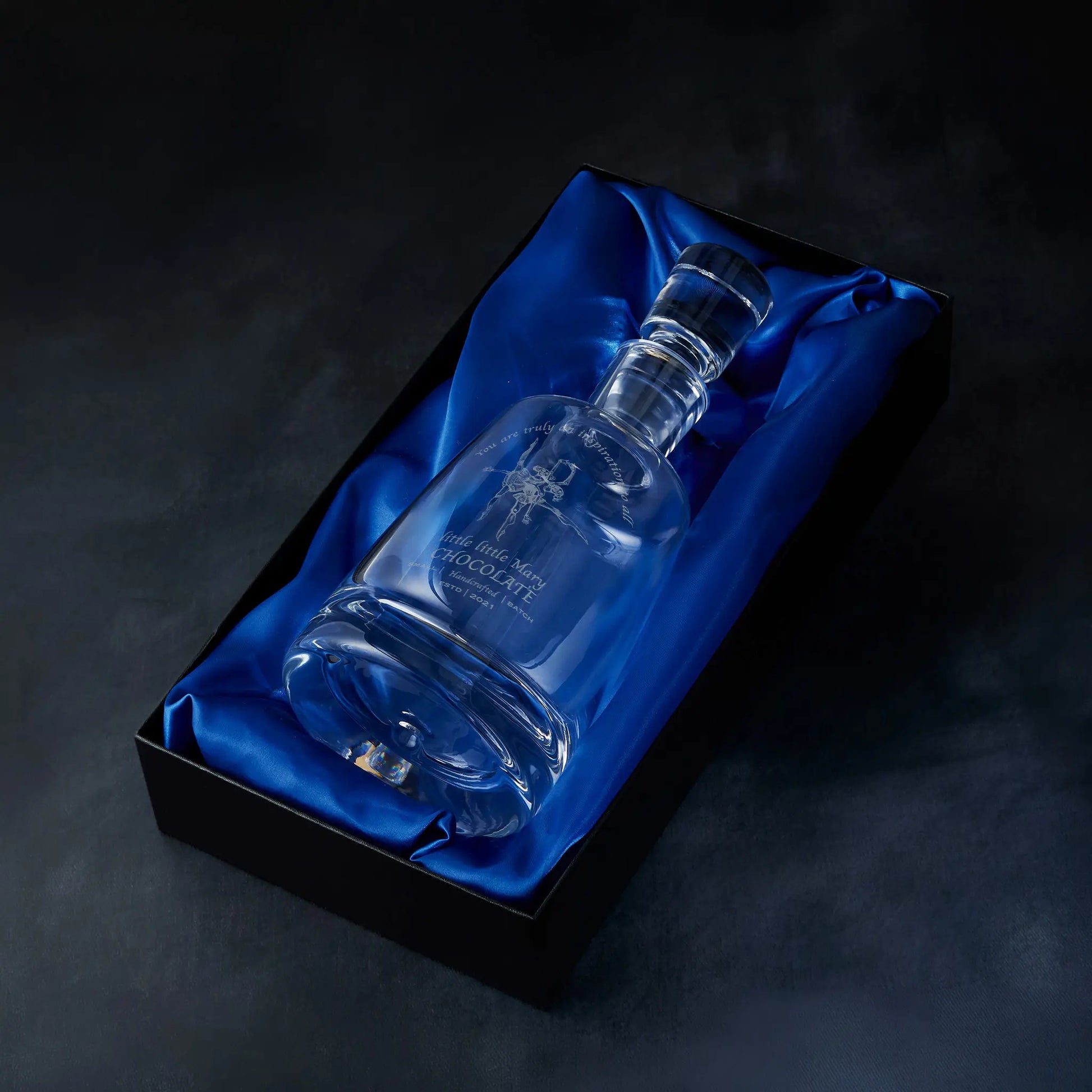 Engraved custom corporate logo spirit decanter presented in a satin-lined gift box, photographed against a deep blue background