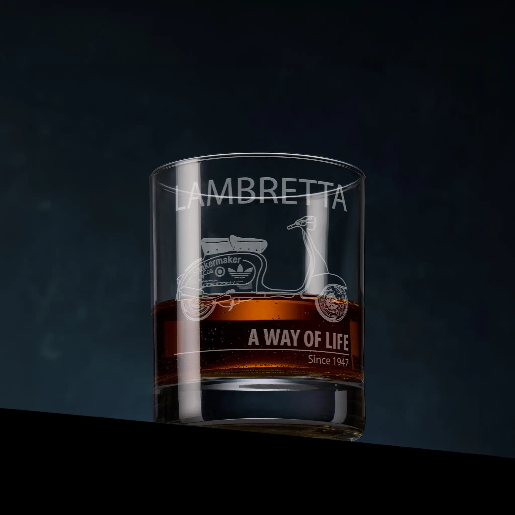 Whisky glass engraved with a Custom Lambretta, photographed on a dark background