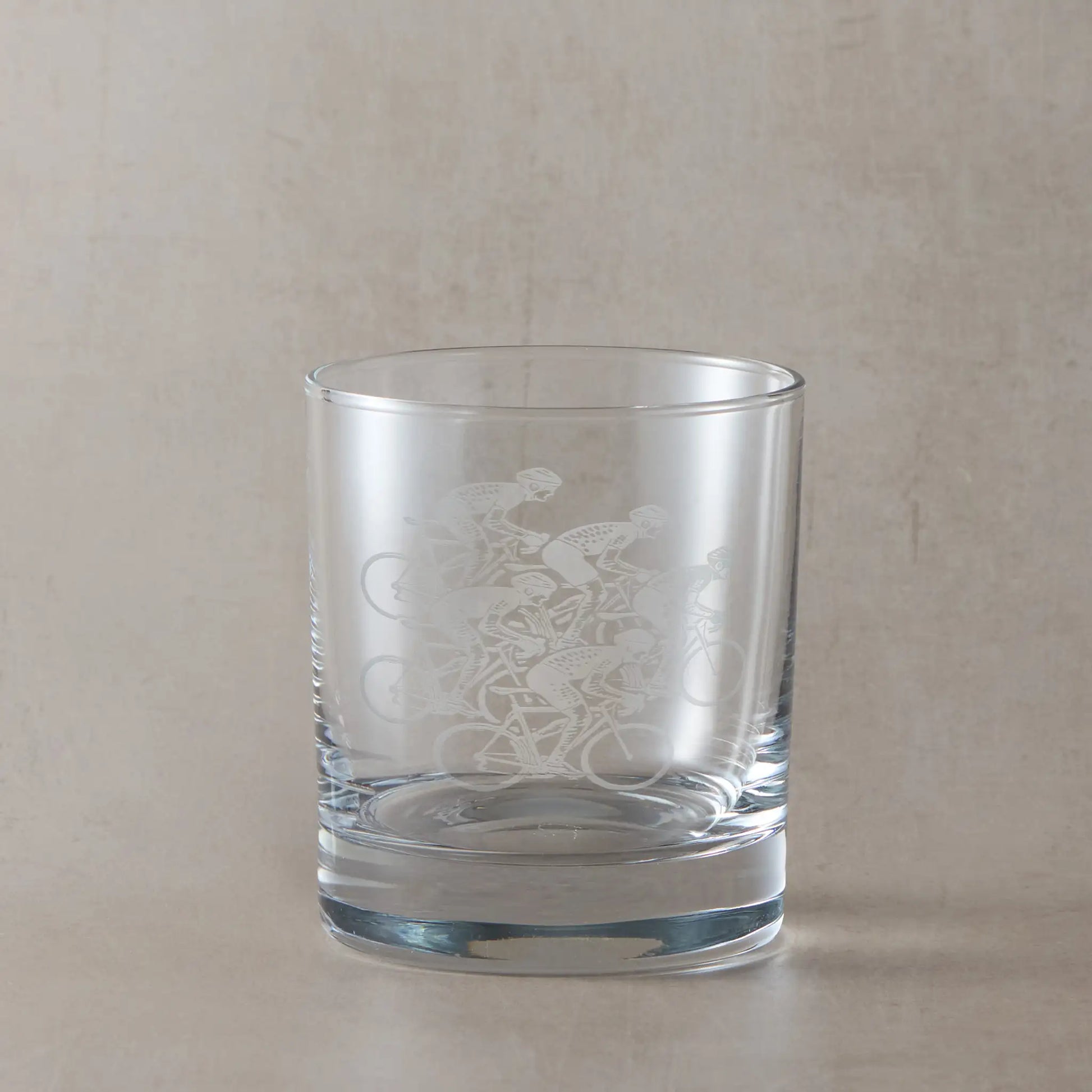 Whisky glass with five road cyclists racing design on a beige background