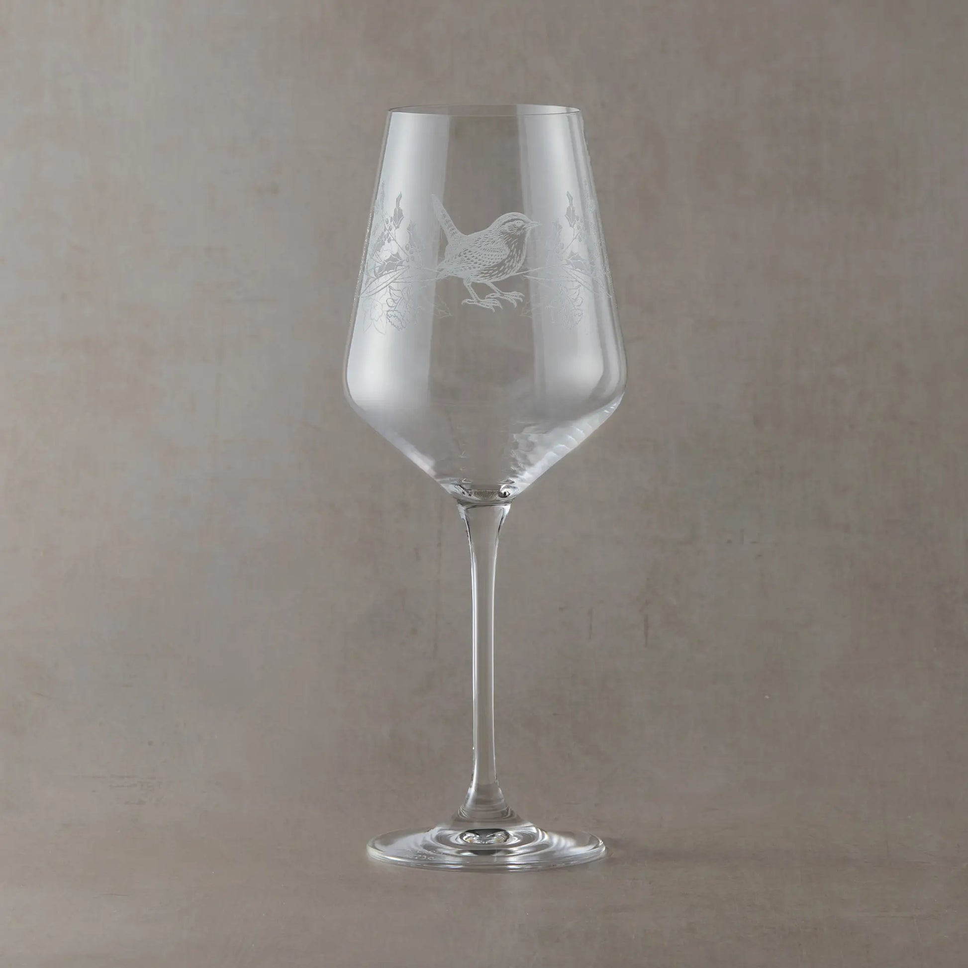 Engraved wine glass featuring December birth flowers with a wren shown on a beige backround