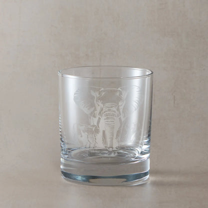 Whisky glass engraved with an Elephant and two calves, photographed on a beige background