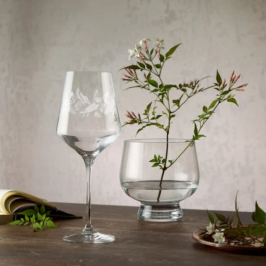Engraved wraparound design of daisies, sweet peas and a puffin on a wine glass