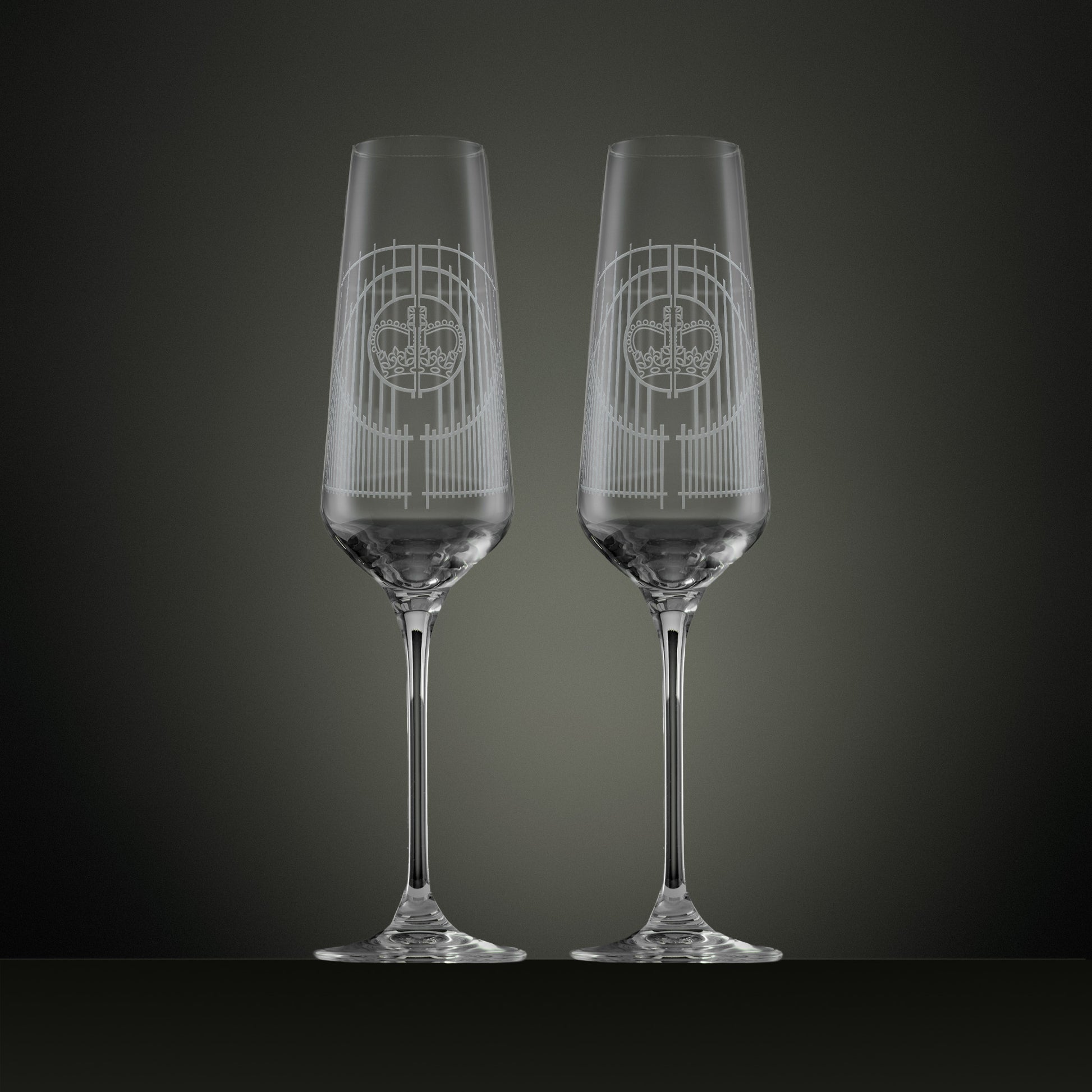 Two engraved champagne flutes with an illustration of the Ascot gates ironwork