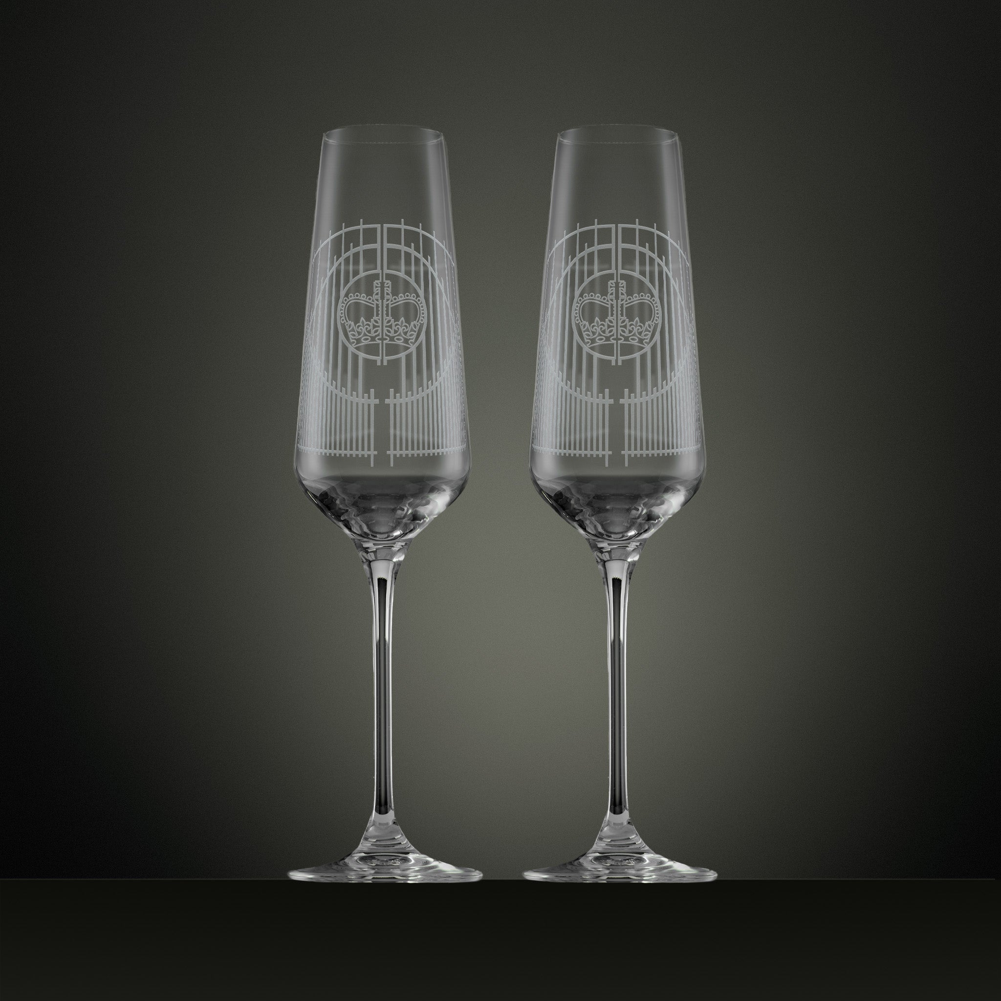 Two engraved champagne flutes with an illustration of the Ascot gates ironwork