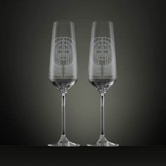 Two engraved champagne flutes with an illustration of the Ascot gates ironwork