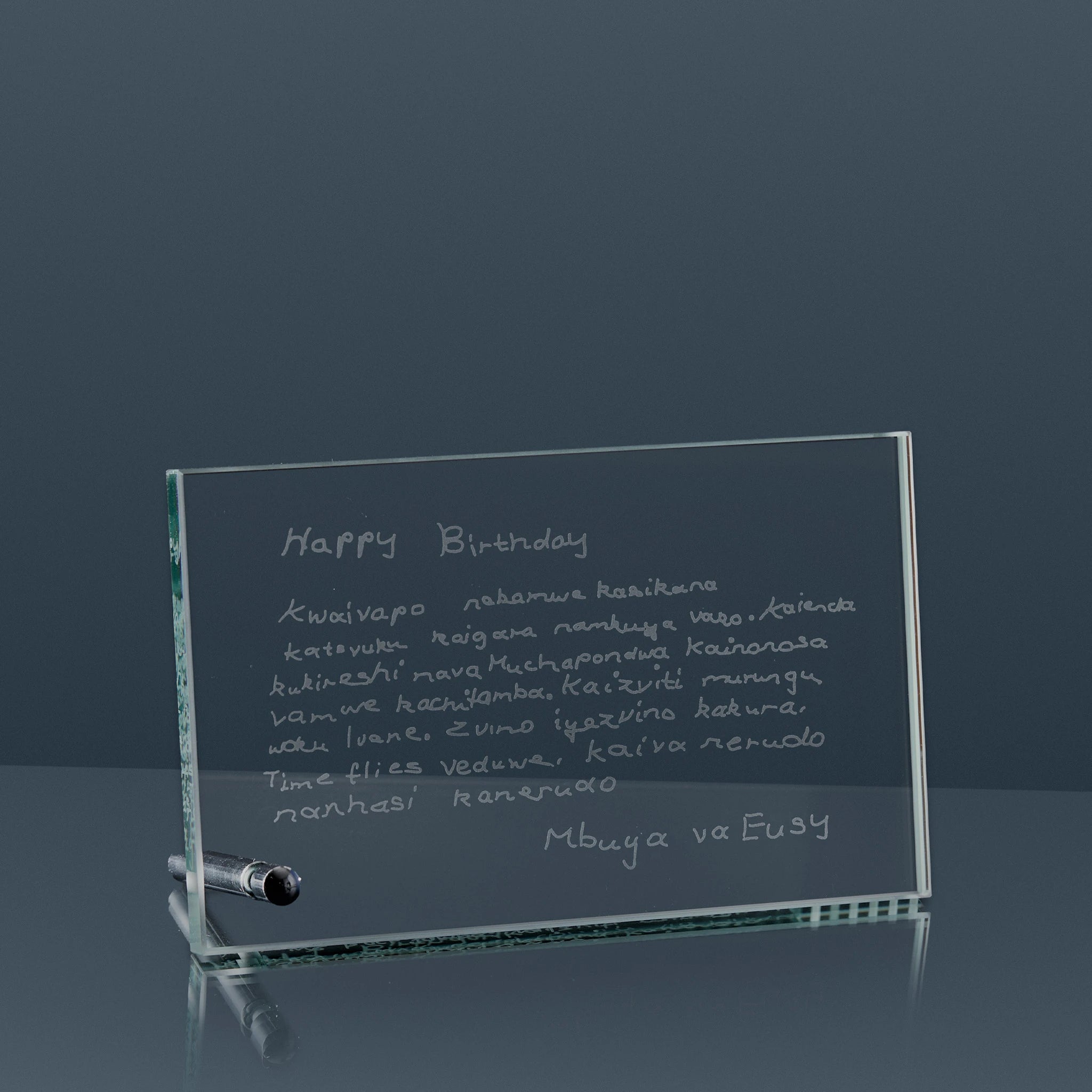 Jade glass plaque with engraved birthday message on a reflective surfacee