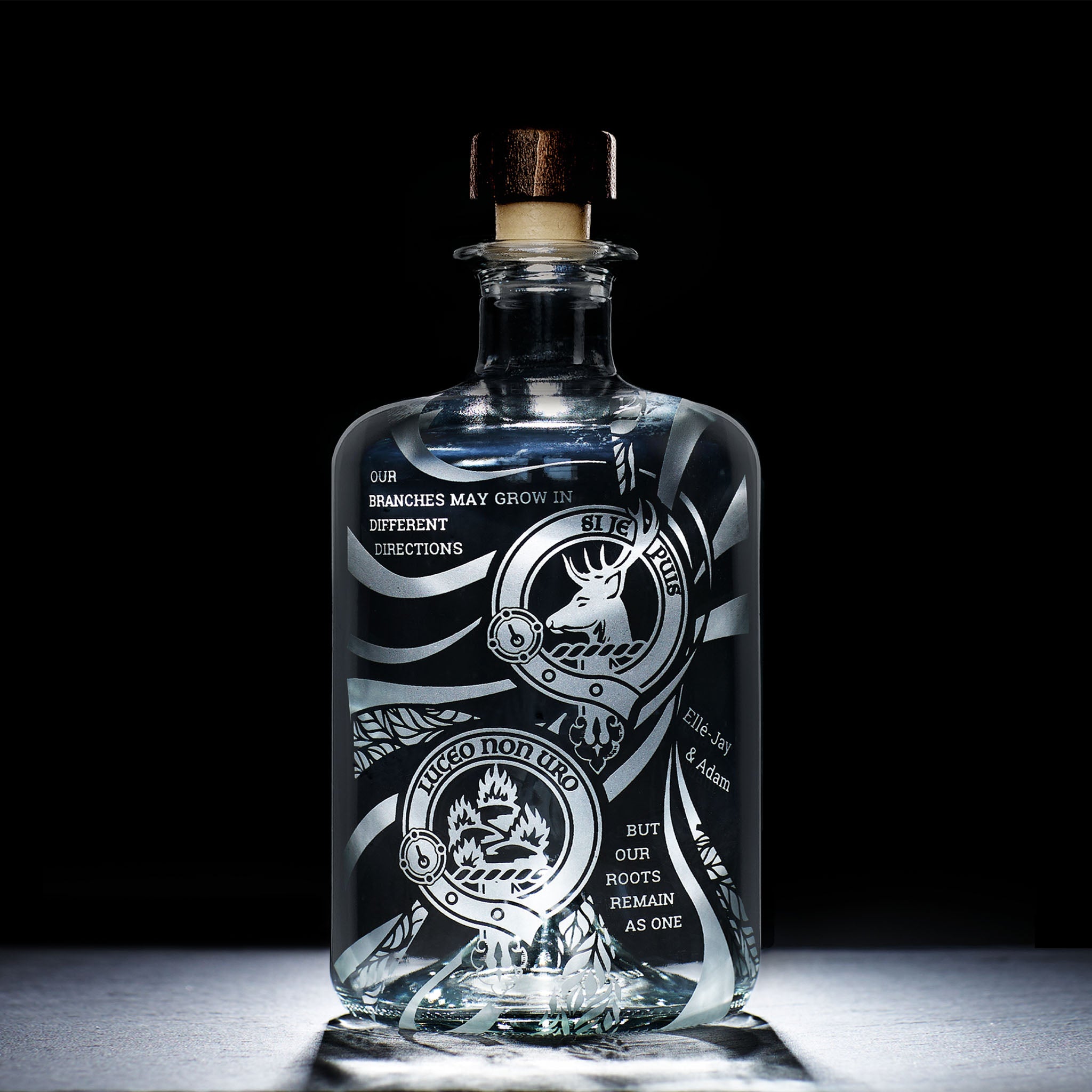 Engraved glass bottle with intricate clan crest designs on a black background