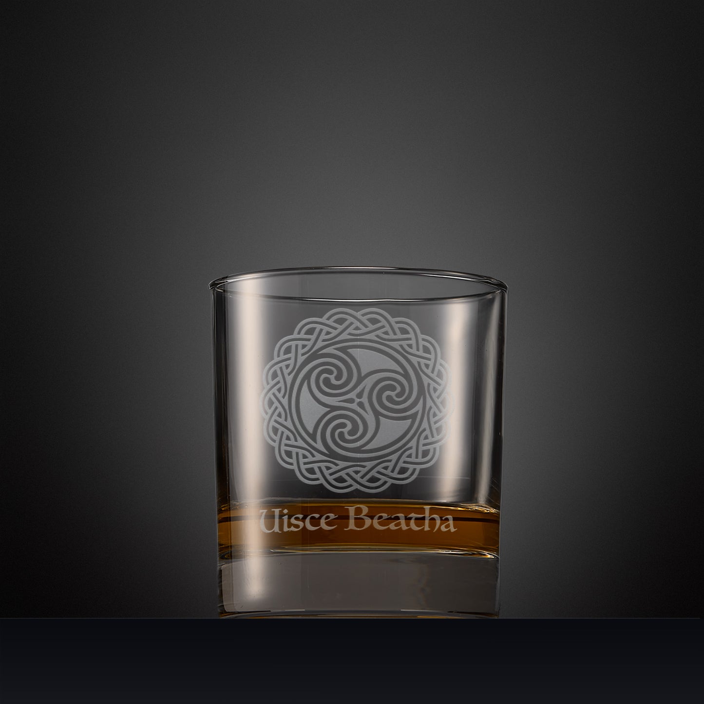 Engraved whisky glass with an  illustration of three interlocking spirals surrounded by Celtic knotwork and Uisce Beatha