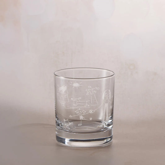 Clear glass tumbler with engraved childs drawing on a beige background