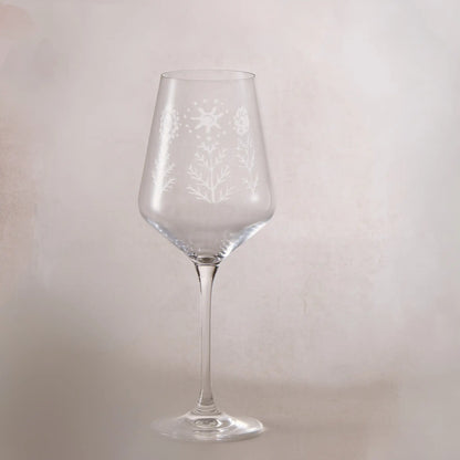 Clear wine glass with engraved childs drawing on a light gray background