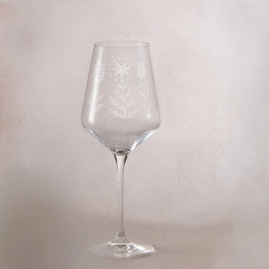 Clear wine glass with engraved childs drawing on a light gray background