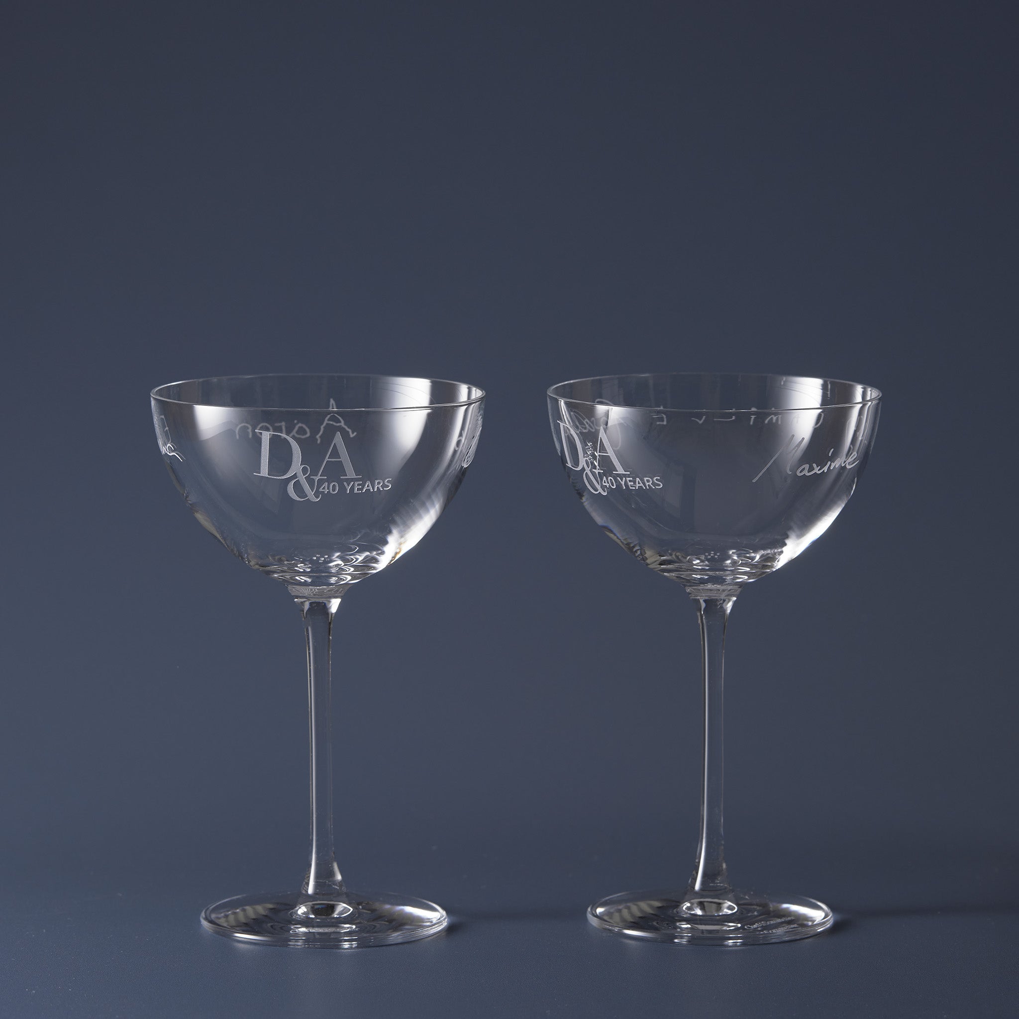 Two clear glass coupes with engraved handwritten names and wedding anniversary inscription