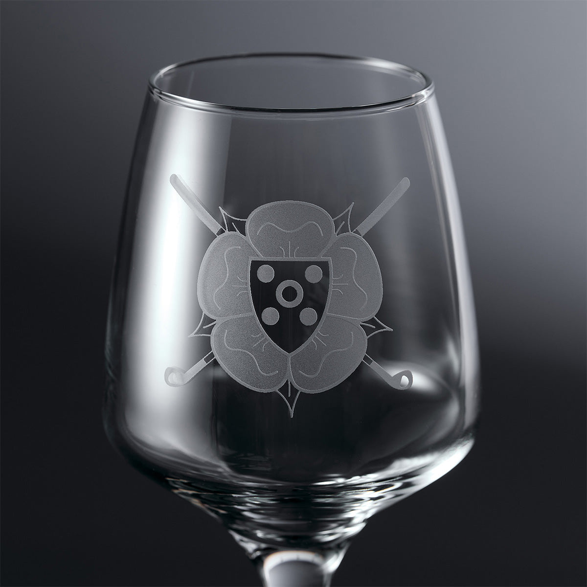 Engraved wine glass with a golf club logo design featuring a shield and crossed golf clubs