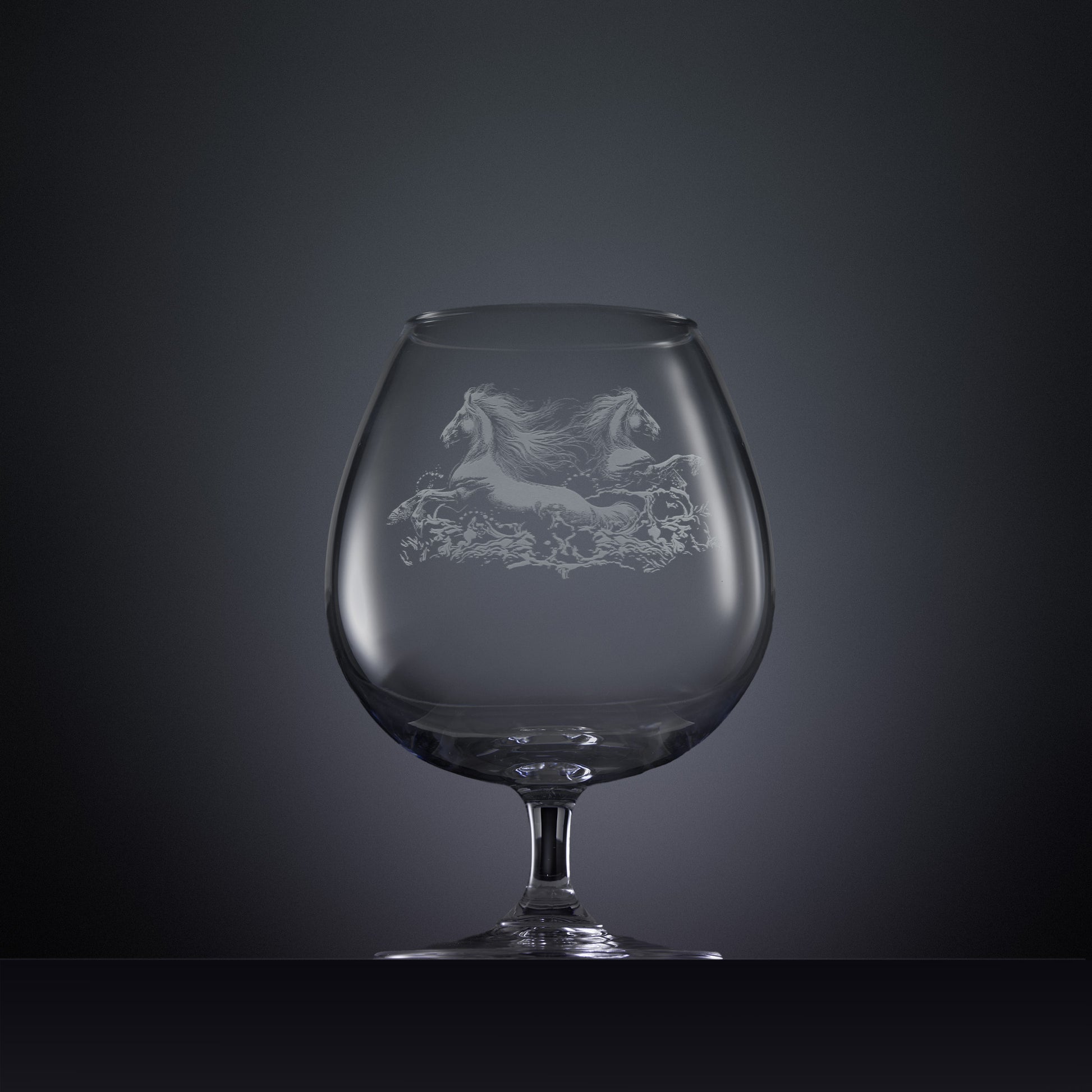Engraved brandy glass with an  illustration of two horses galloping through the water