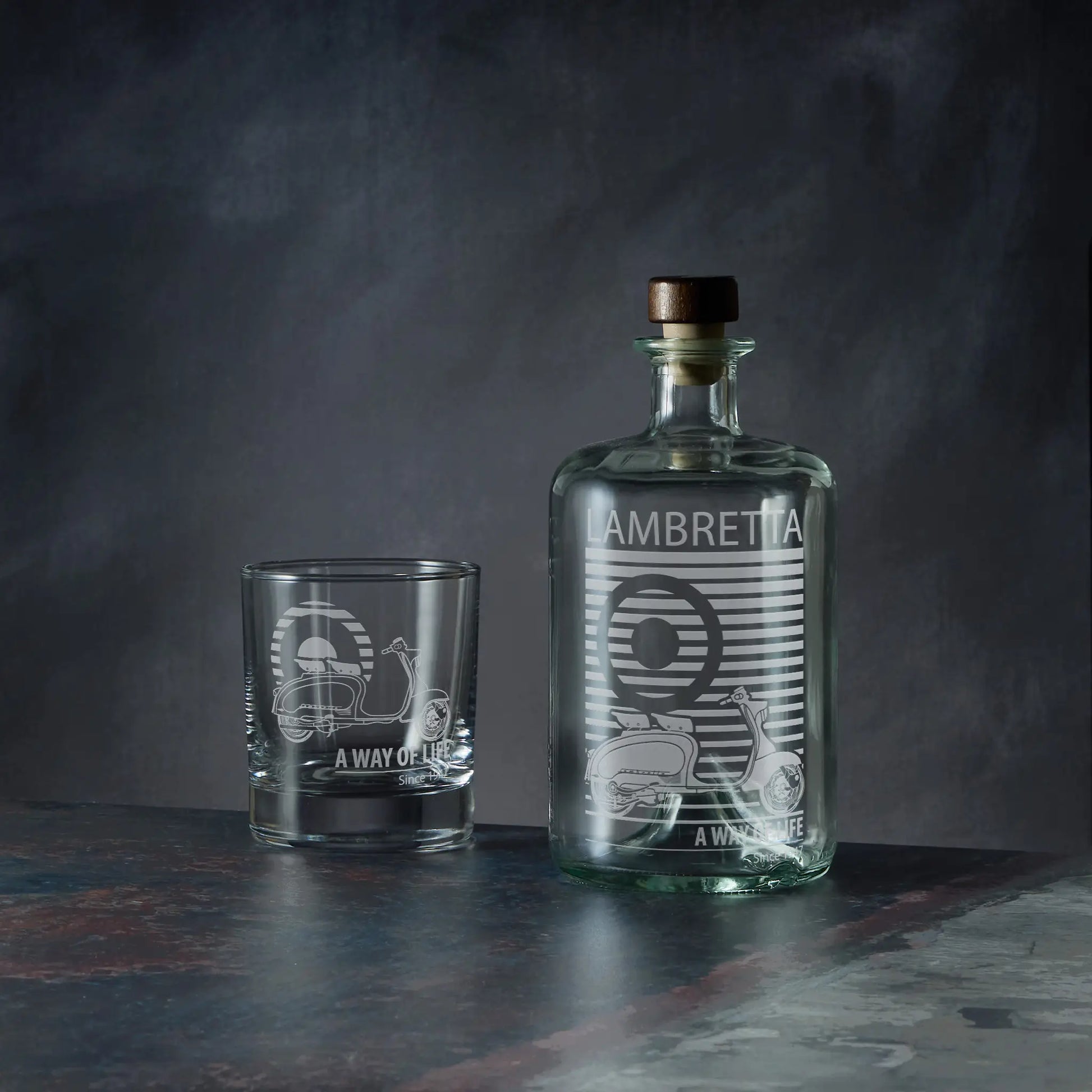 A clear glass decanter bottle and matching tumbler glass with etched vintage Li 125 scooter and striped Lambretta text.