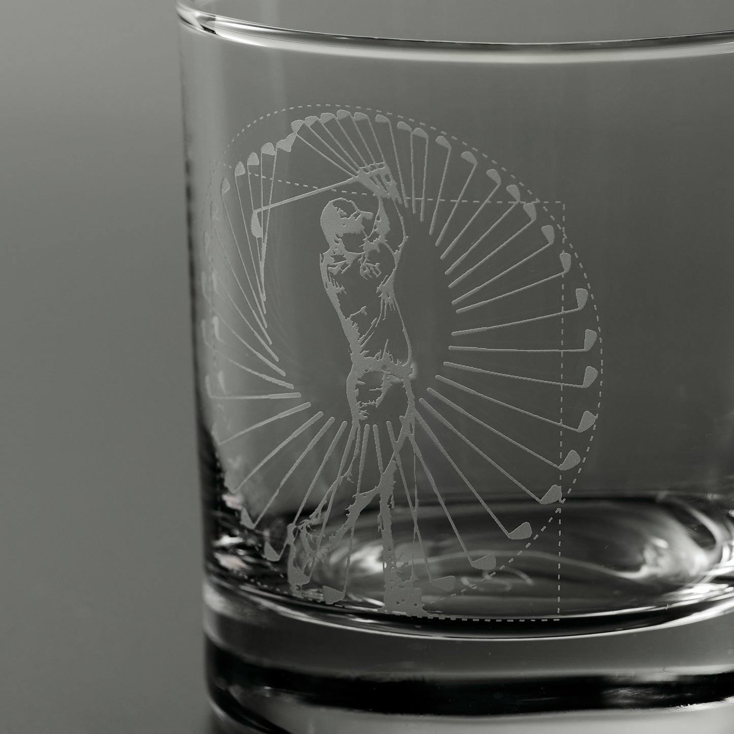 Engraved whisky glass featuring a golfer mid swing inside a circular pattern og golf clubs