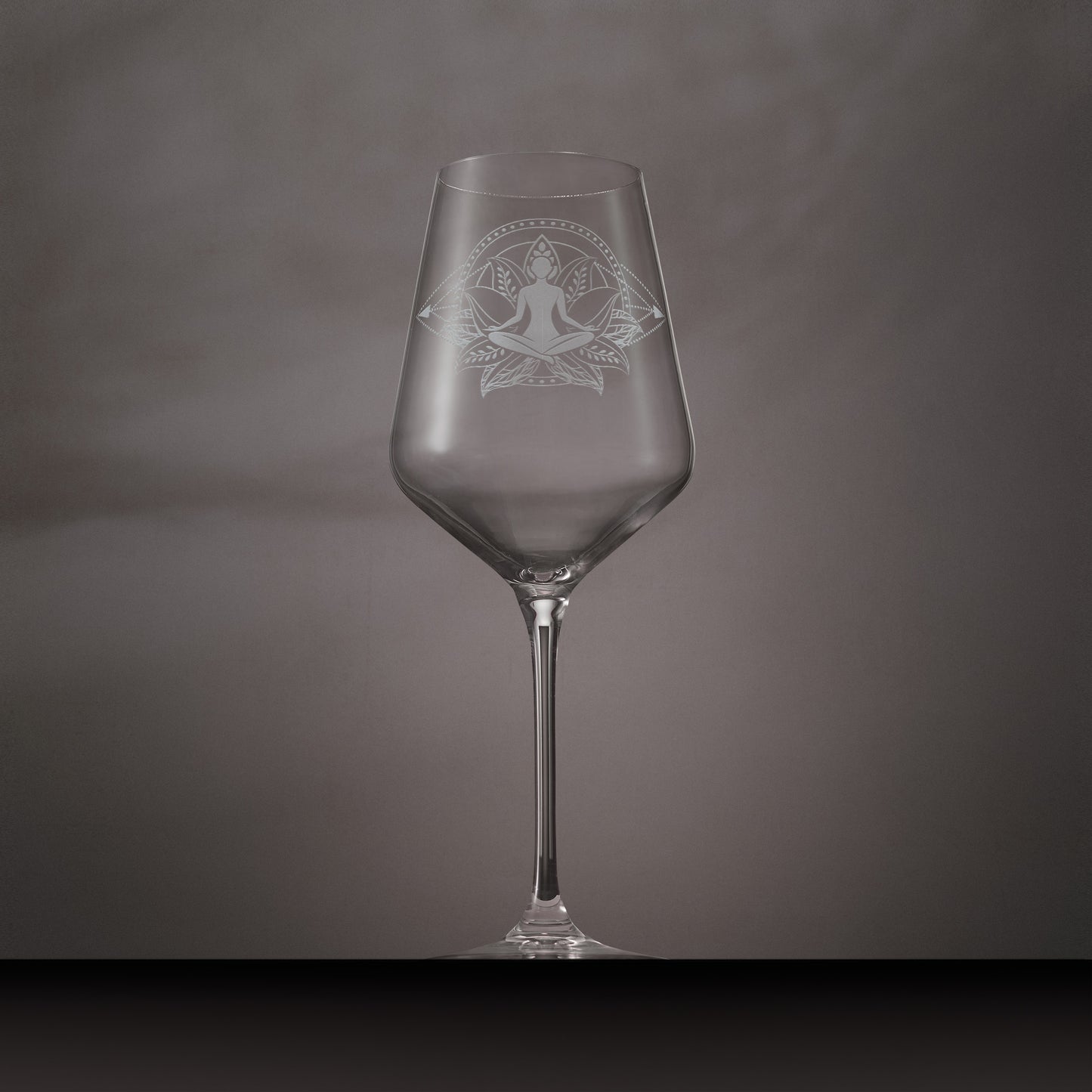 Engraved wine glass featuring Sukhasana yoga pose seated in a lotus flower with mandala-style circles and dotted diamond design