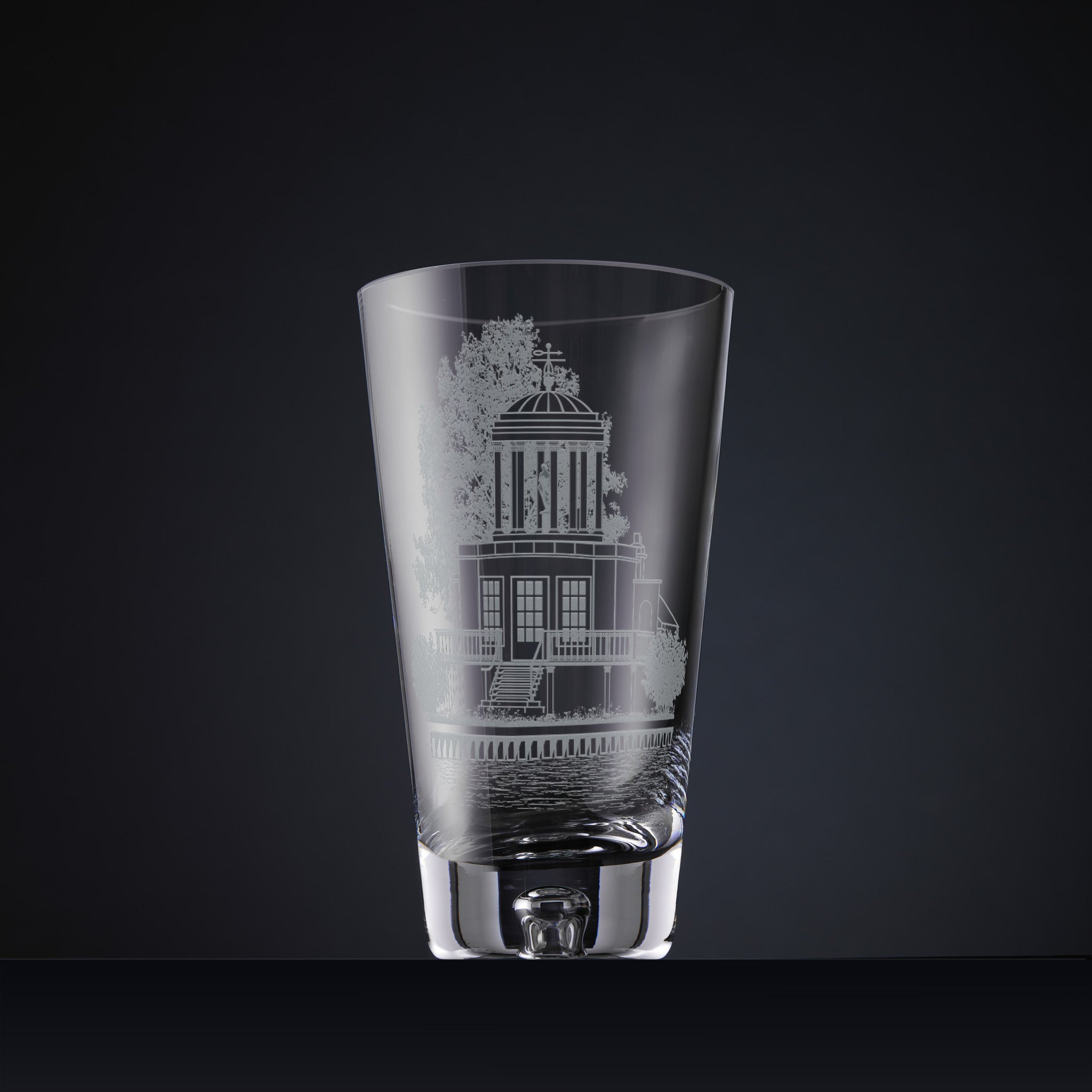 A clear glass vase with an etched architectural house design on the front.