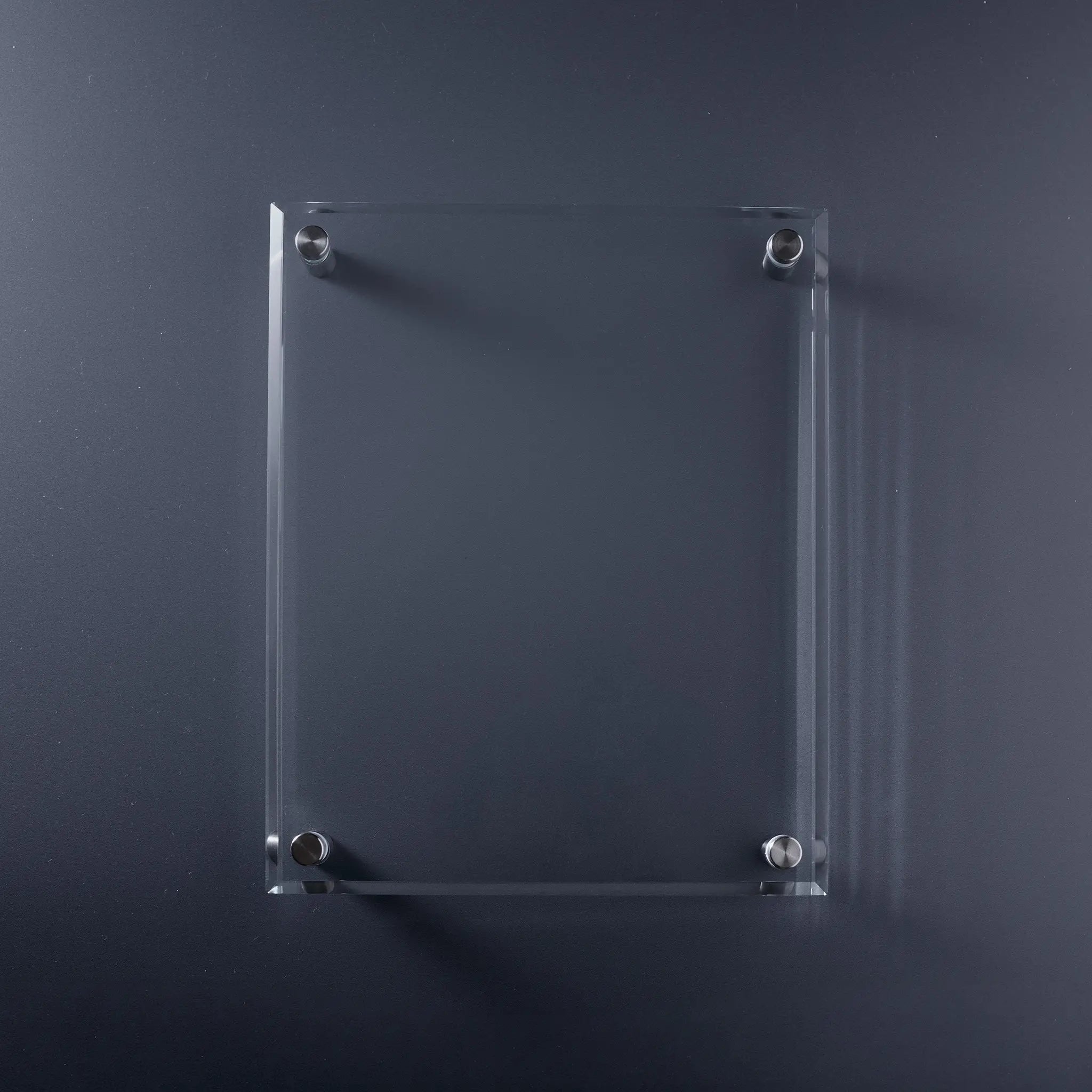 A clear rectangular glass display plaque with bevelled edges and four silver metal mounting screws.