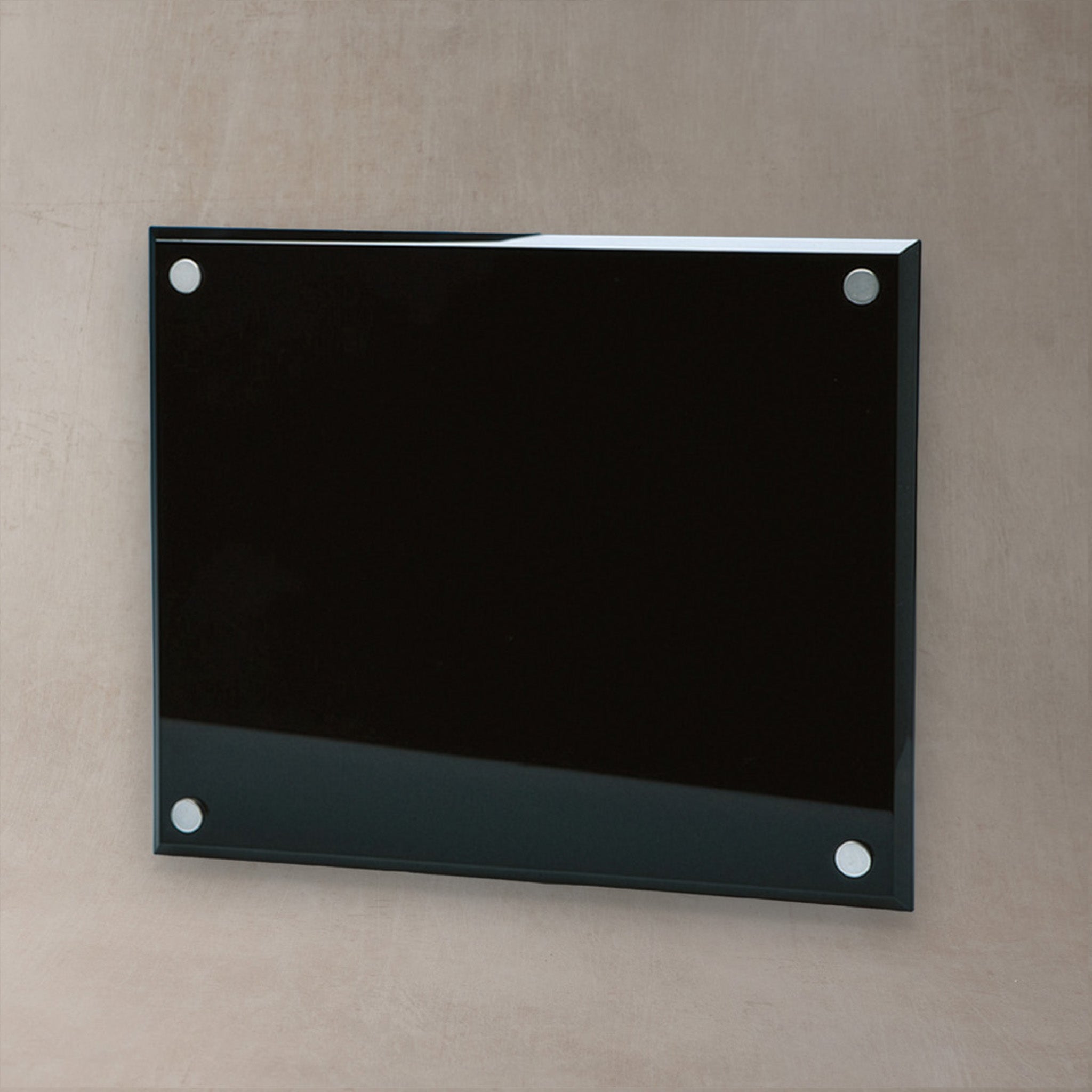 A rectangular glossy black glass plaque and four silver metal mounting dots, mounted on a textured beige wall.