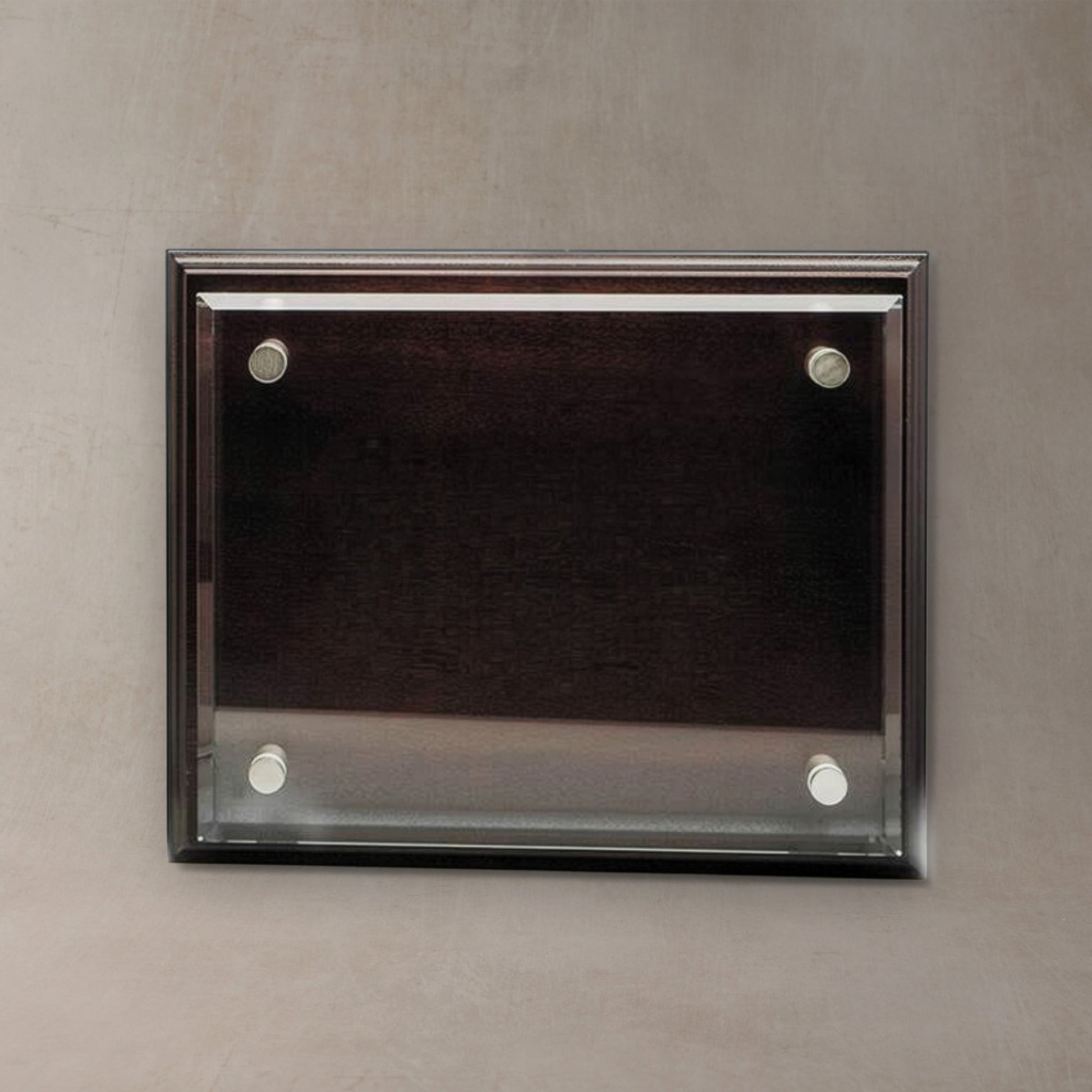 A rectangular wall-mounted display plaque with a dark wood frame and four silver wall anchors, shown against a textured gray wall.