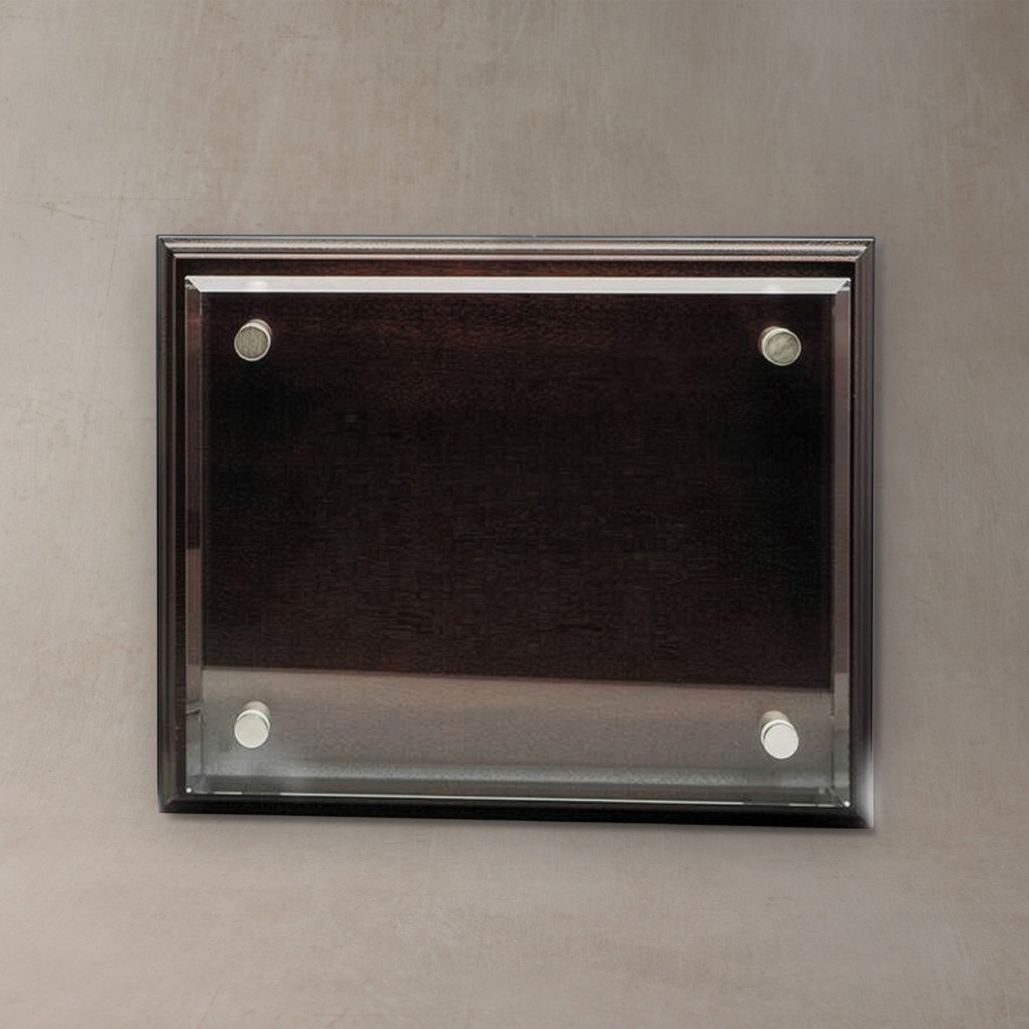 A rectangular wall-mounted display plaque with a dark wood frame and four silver wall anchors, shown against a textured gray wall.