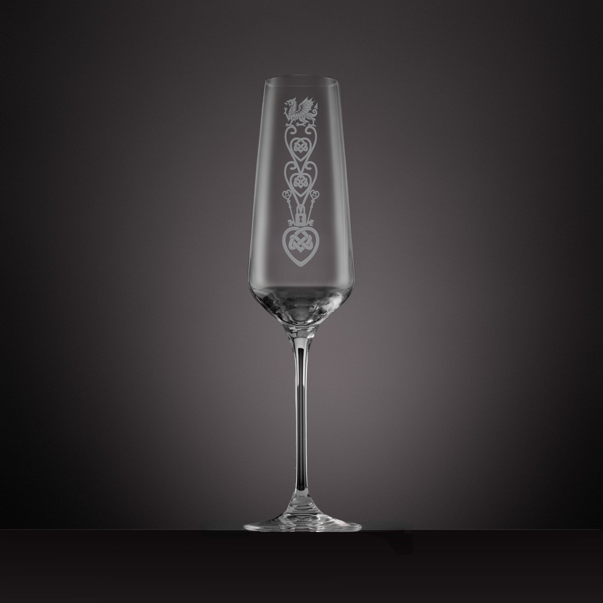 Engraved glass champagne flute featuring a celtic knotwork lovespoon and Welsh Dragon design