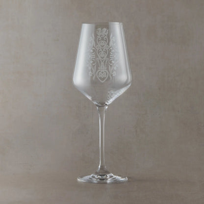 A clear wine glass with an etched floral welsh lovespoon design on the bowl