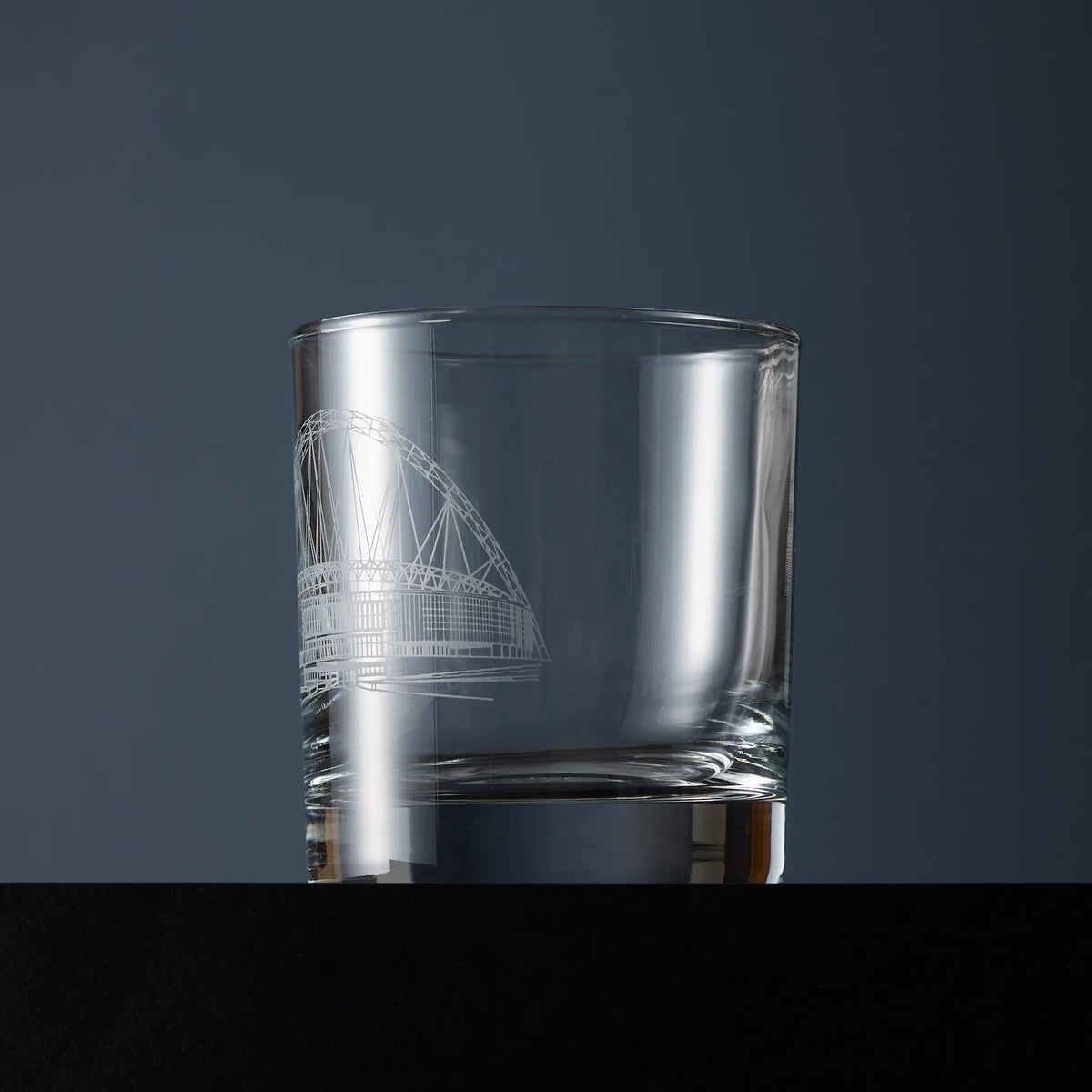 Side view of a clear glass whisky tumbler engraved with the National Stadium at Wembley illustration