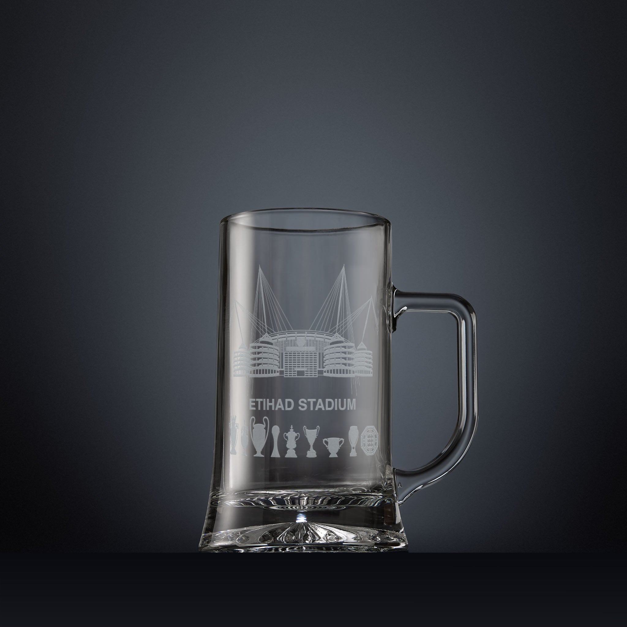 Glass tankard engraved with a line-art interpretation of the Etihad Stadium, with football trophy silhouettes beneath