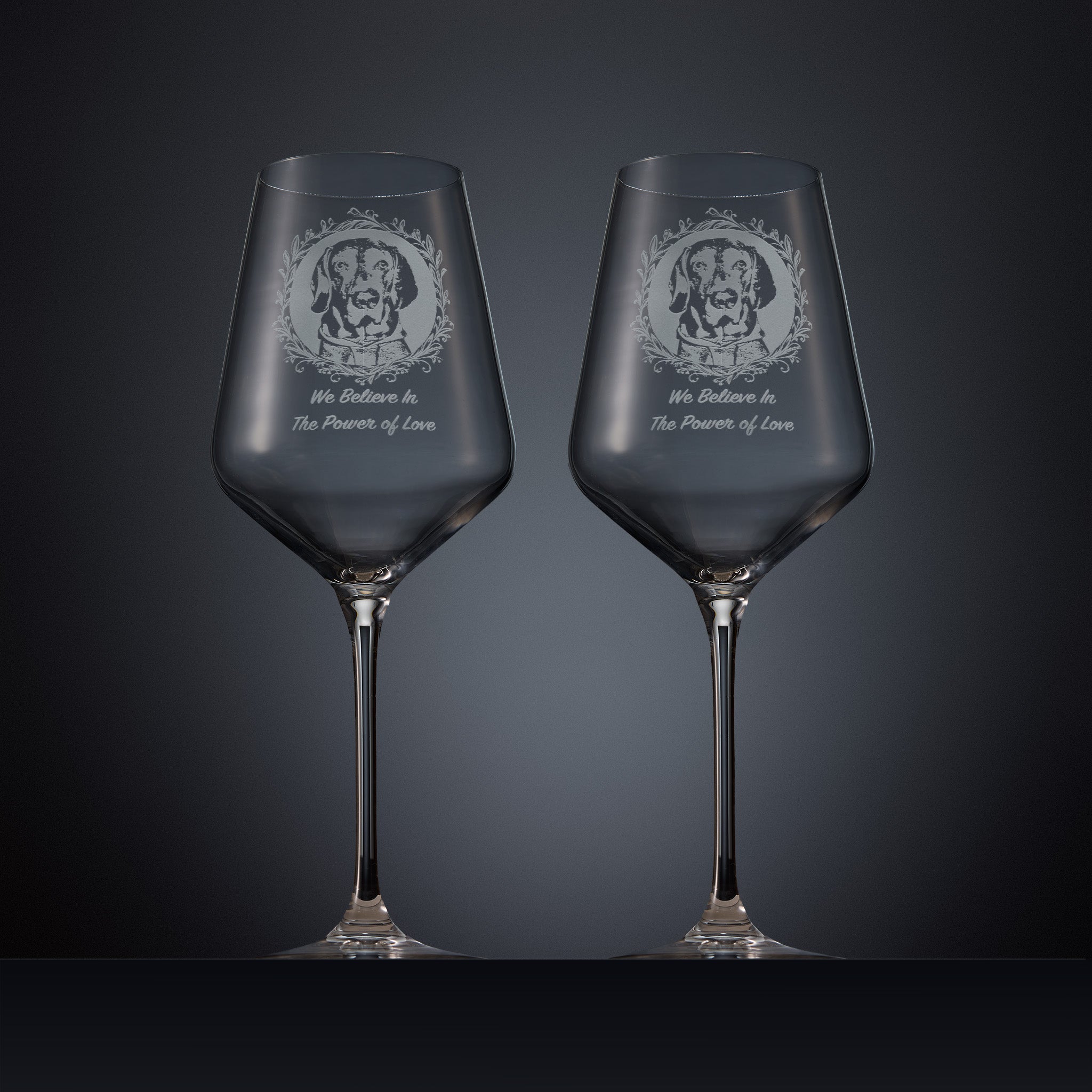 Two clear wine glasses with engraved dog portraits and the text 'We Beleive In The Power of Love' 