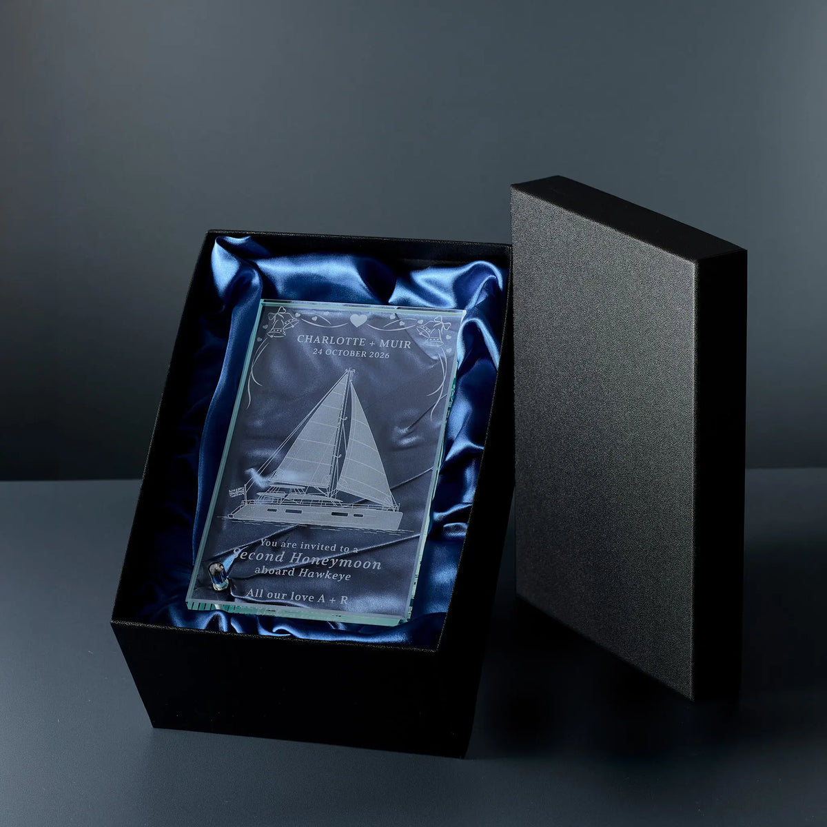 An engraved glass plaque displayed inside an open black presentation box with blue satin lining.