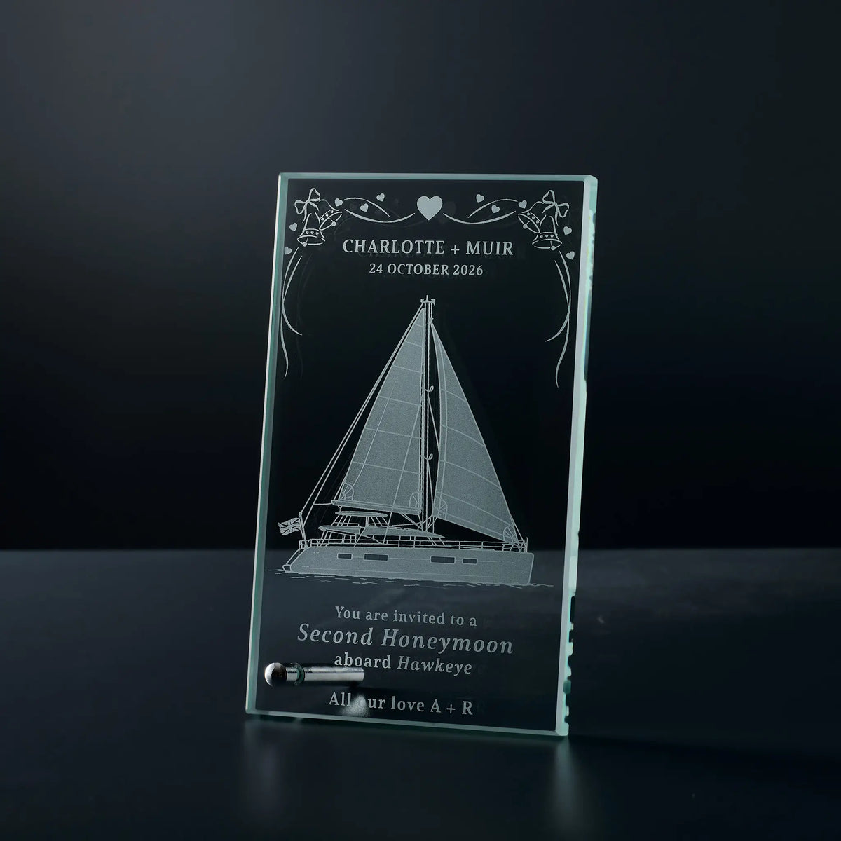 A personalised clear glass dispaly plaque featuring an engraved sailboat design and custom text.