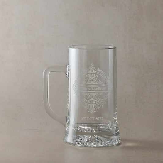 Father of the bride engraved glass tankard personalised with names and date, ona plae background.
