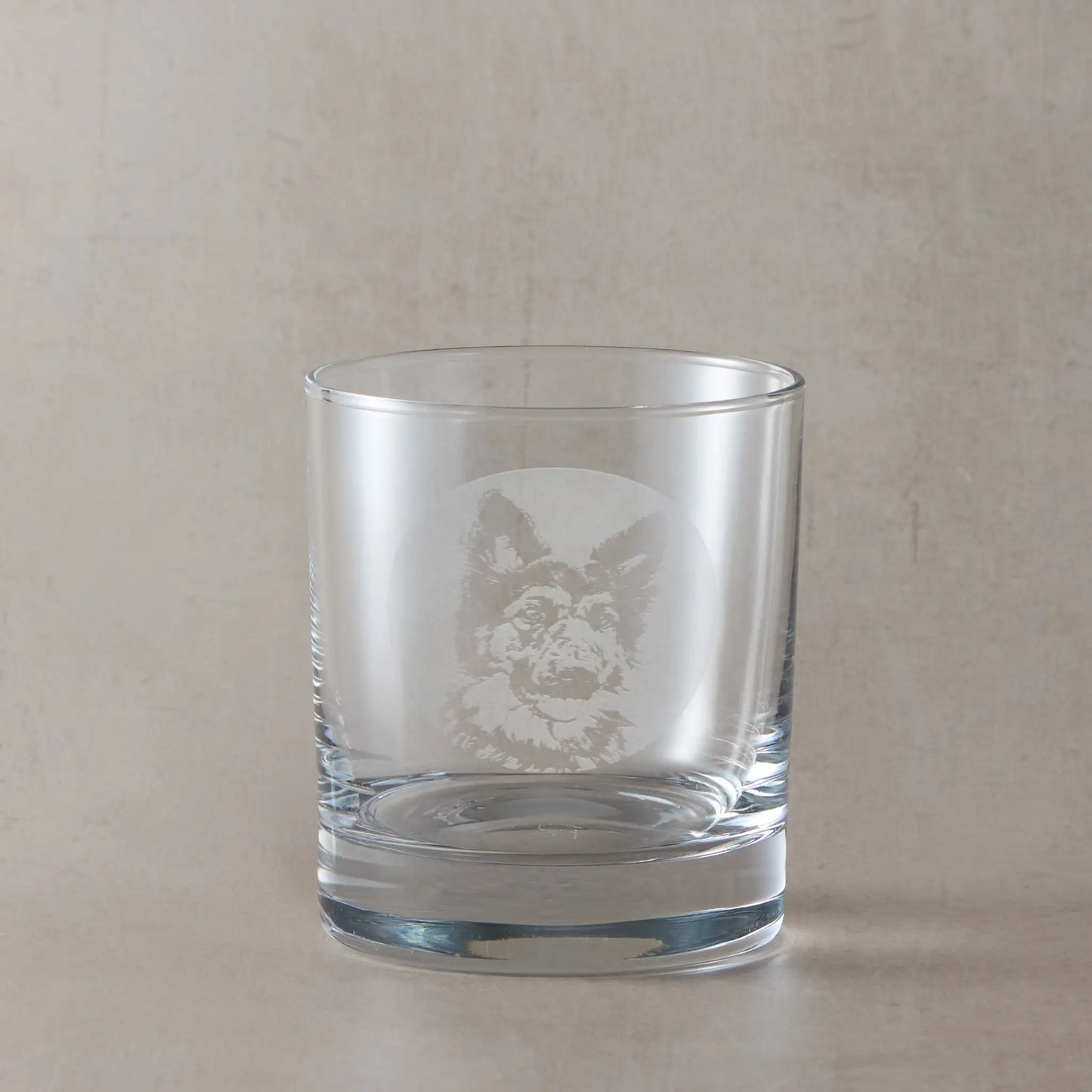 Whisky glass with engraved portrait of a German Shepherd, on a beige background