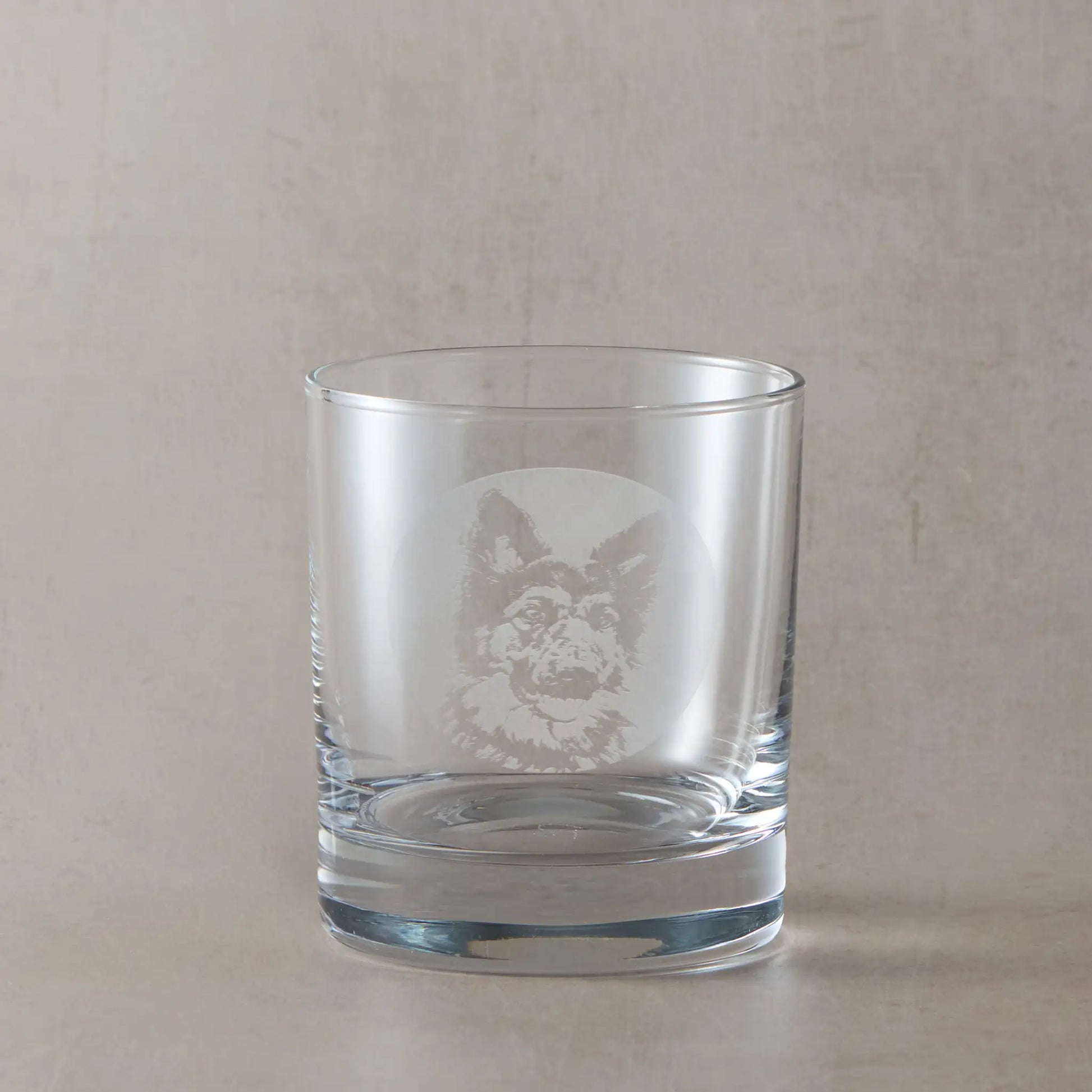 Whisky glass with engraved portrait of a German Shepherd, on a beige background