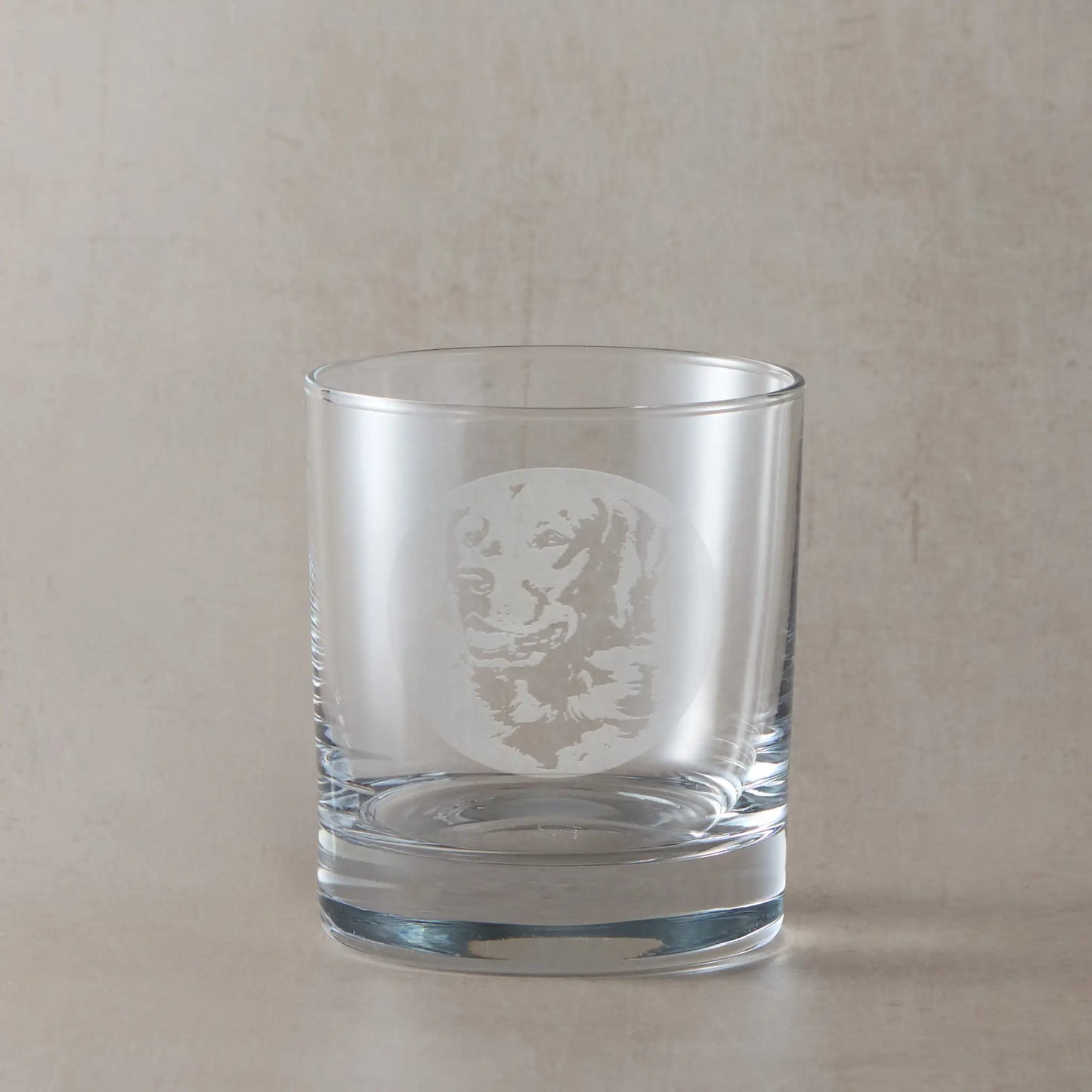 Whisky glass with engraved portrait of a Golden Retriever, on a beige background
