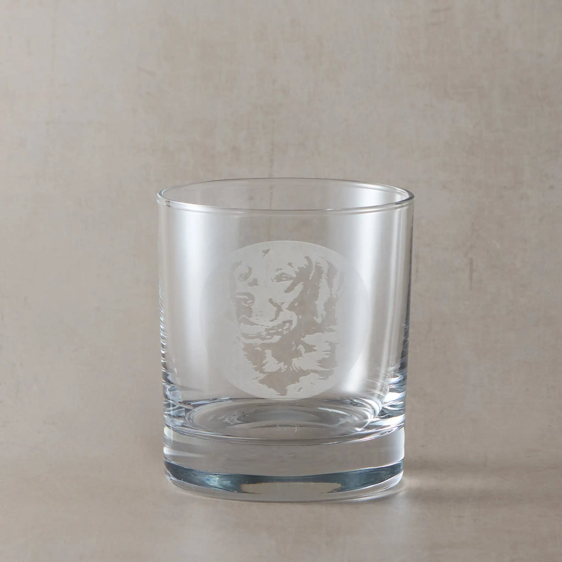 Whisky glass with engraved portrait of a Golden Retriever, on a beige background