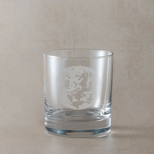 Whisky glass with engraved portrait of a Golden Retriever, on a beige background