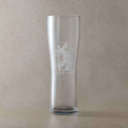 Pint glass engraved with the "The 19th Hole  and silhouette of a golfer mid-swing.